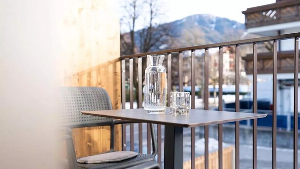 Ein Balkon mit Tisch, Stuhl und einer Vase.
