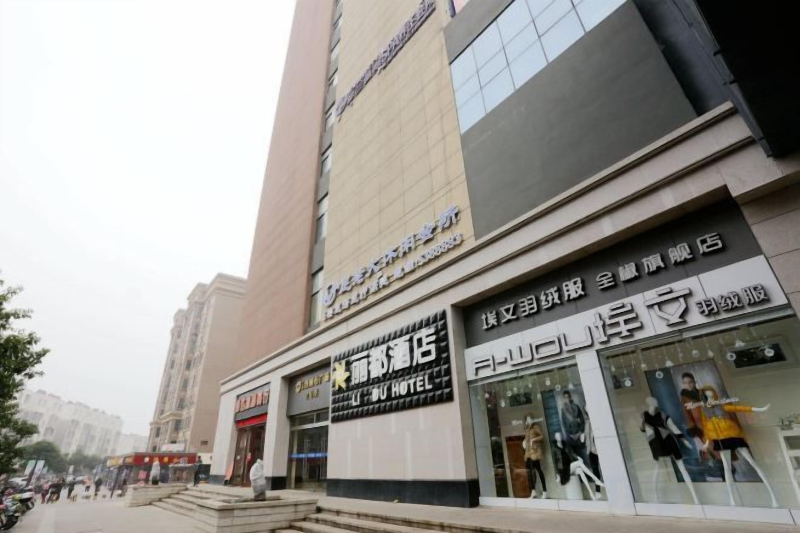 A hotel with a modern facade, multiple storefronts on the ground floor, and a staircase leading to the entrance.
