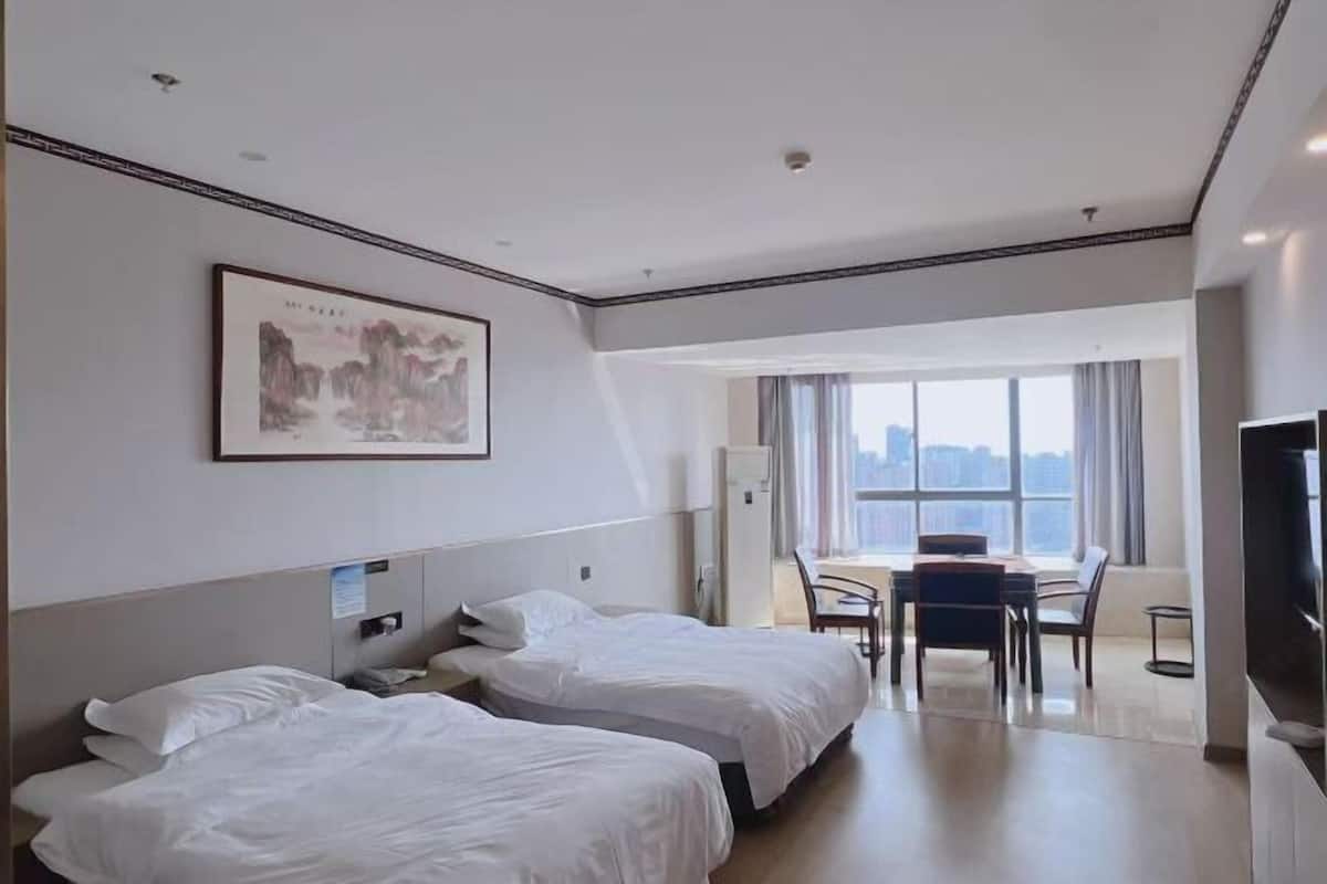 A hotel room with two beds, a desk, and a TV.