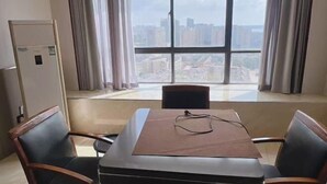 Una habitación de hotel con un ventanal grande, una mesa con sillas y un refrigerador.