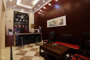 Un hall de hotel con mostrador de recepción, zona de estar y piso a cuadros.