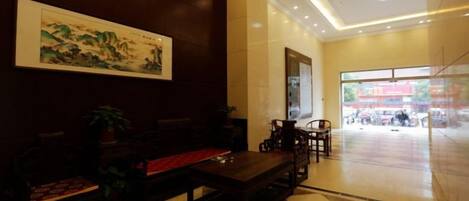 A lobby with a checkered floor, a reception desk, and a painting on the wall.