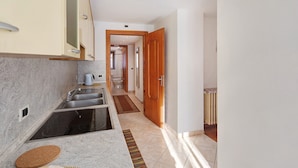 A kitchen with a sink, stove, and a wooden door leading to another room. - Gg 2 Apartment – Central Livigno, Gold Discount Card for Local Services Included (Livigno)
