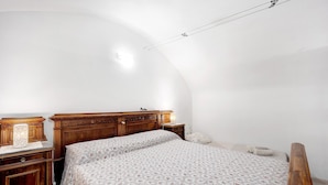 A bedroom with a wooden bed, a nightstand, a lamp, and a curved ceiling. - Apartment 'La Casa Tonda' (dolceacqua)