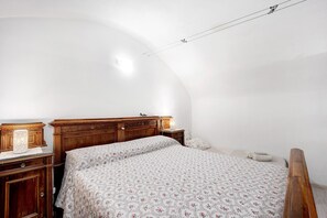 Ein Schlafzimmer mit einem hölzernen Bett, einem Nachttisch, einer Lampe und einer gewölbten Decke.