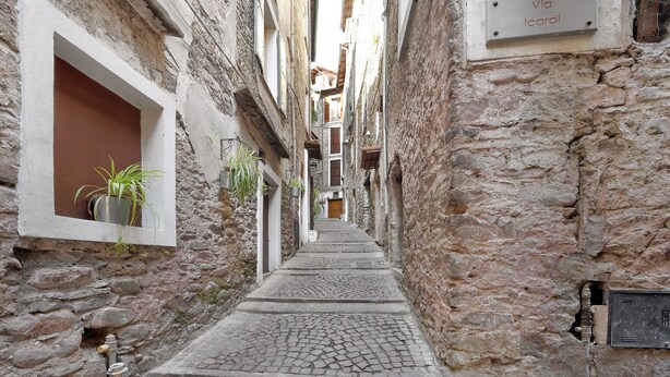 A narrow stone alleyway with a cobblestone path, potted plants, and a sign reading 'Via Icaridi'. - Apartment 'La Casa Tonda' (dolceacqua)