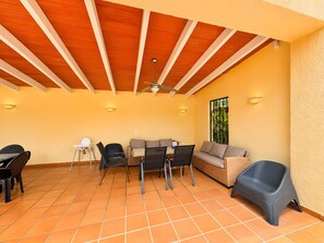 A covered patio area with a wooden ceiling, tiled floor, and seating arrangements including a sofa and chairs. - Villa "Casa Emilia" with Pool, Garden and Wi-Fi (Moraira)