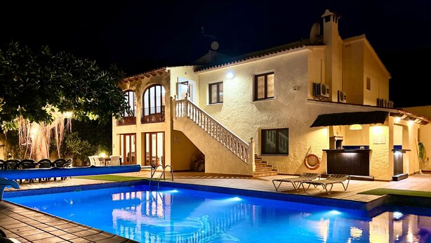 Una piscina con solárium de azulejos, una escalera que lleva a un balcón y una zona de recepción con mostrador.