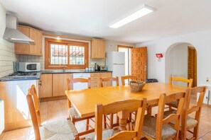 A kitchen with wooden cabinets, a stove, a microwave, and a dining table with chairs.
