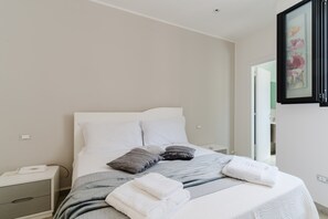 Une chambre à coucher avec un lit, des oreillers, une table de chevet et une commode.