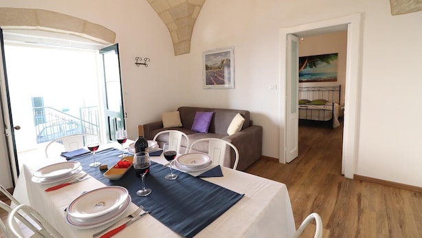 Un coin repas avec une table dressée pour deux personnes, un canapé et un tableau accroché au mur.