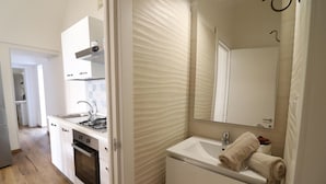 Une cuisine compacte équipée d’une cuisinière à gaz, d’un four et d’un évier, ainsi qu’une salle de bain avec un lavabo, un miroir et des serviettes.