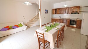 A modern kitchen with wooden cabinets, a dining table set for four, and a staircase leading to an upper floor. - Holiday Apartment "Rita" with Air Conditioning and Terrace (Otranto)