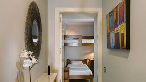 Una habitación con una litera, una mesita de noche, un espejo y un cuadro en la pared.