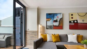 Una sala de estar moderna con un sofá gris, cojines amarillos, una mesa de centro de madera y arte abstracto en la pared.