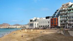 Una playa con edificios, cielo despejado y gente.