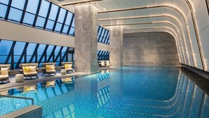 An indoor swimming pool with clear blue water, modern lounge chairs, and large windows allowing natural light. - Crowne Plaza Quanzhou Riverview by IHG (Quanzhou)