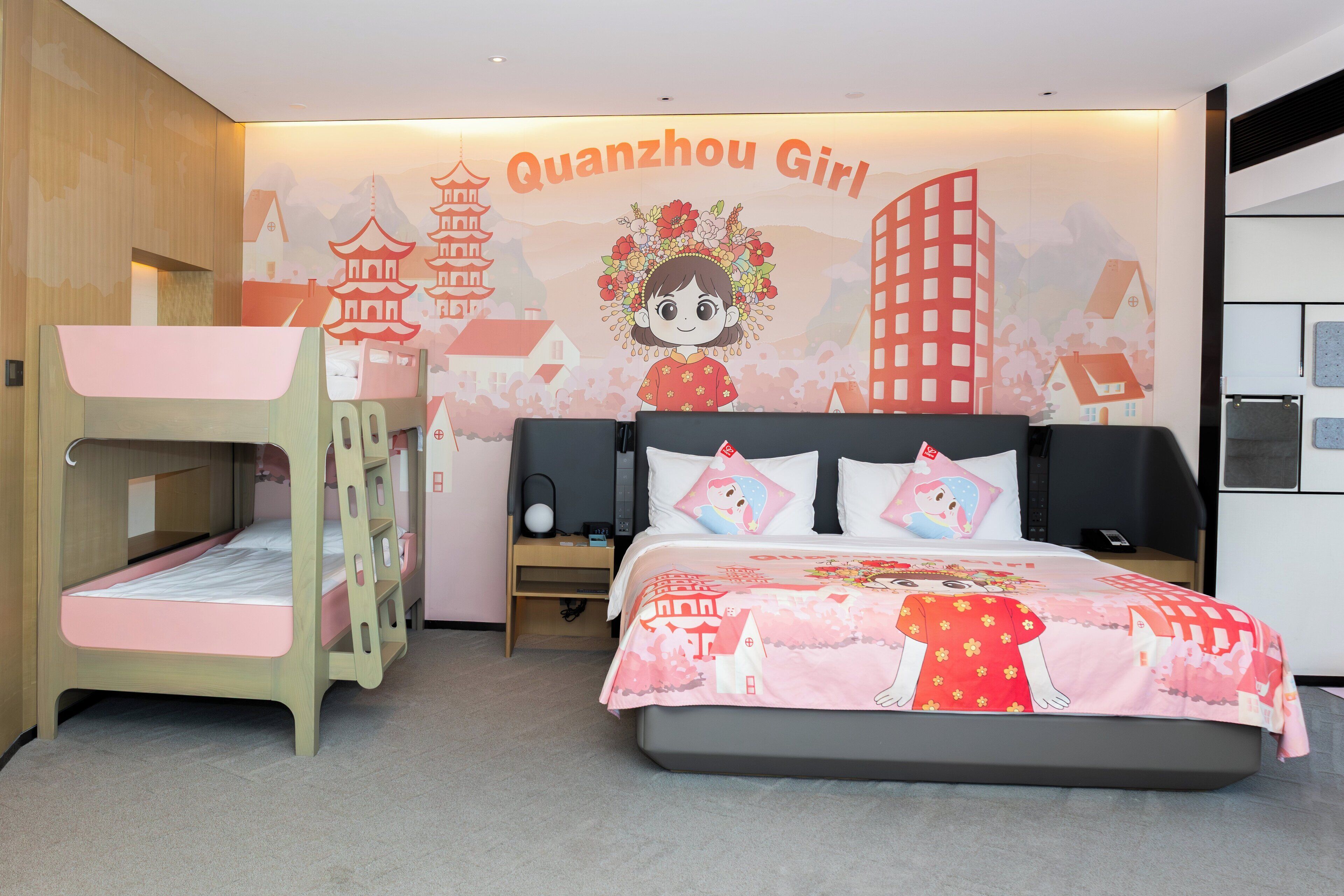 Habitación de hotel ideal para niños, con literas, una cama grande con cubrecama colorido y un mural en la pared que muestra un personaje de dibujos animados y arquitectura china.