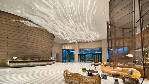 A spacious lobby with a curved reception desk, modern wicker furniture, and a unique ceiling design. - Crowne Plaza Quanzhou Riverview by IHG (Quanzhou)