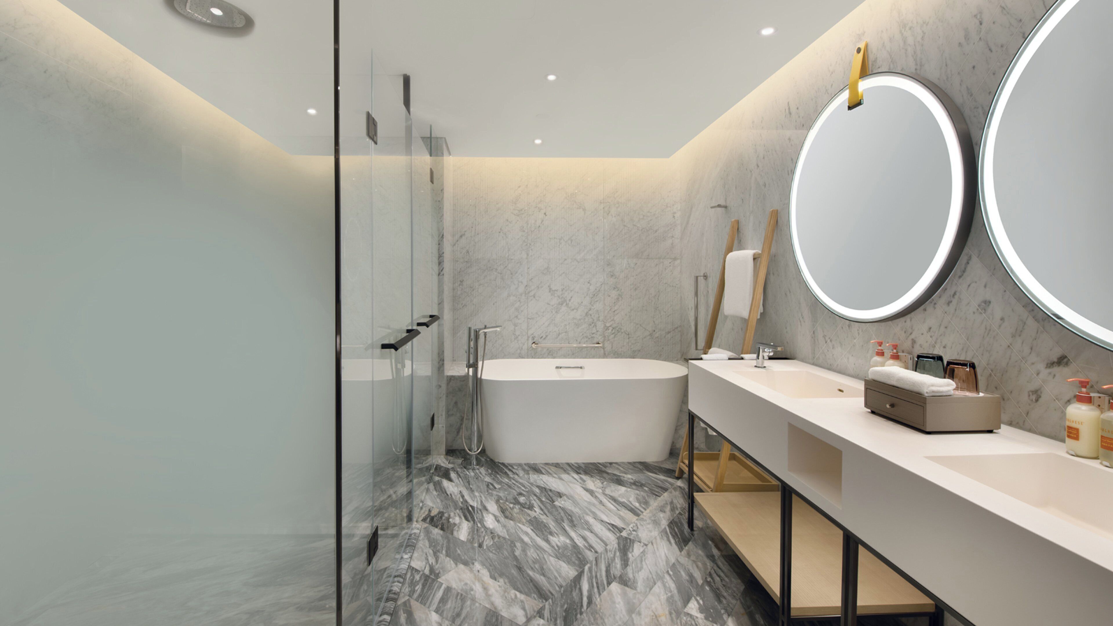 Un baño moderno con cabina de ducha de vidrio, bañera independiente y tocador con un espejo grande.