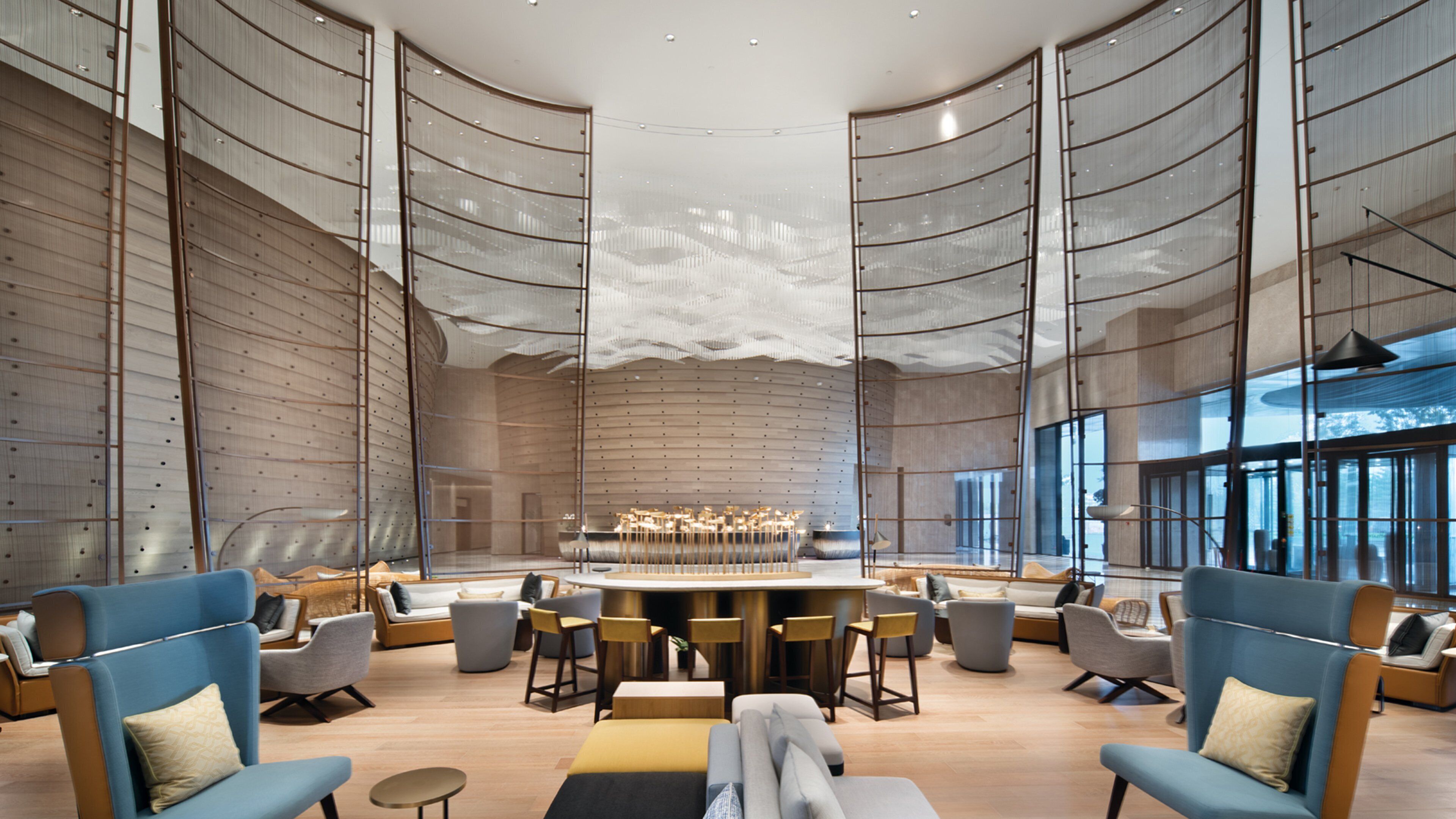 A spacious lobby with a central bar area, seating arrangements, and large windows providing natural light.