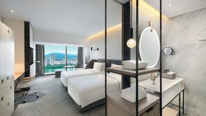 Habitación de hotel con una cama grande, un escritorio, un espejo y vistas a la ciudad.