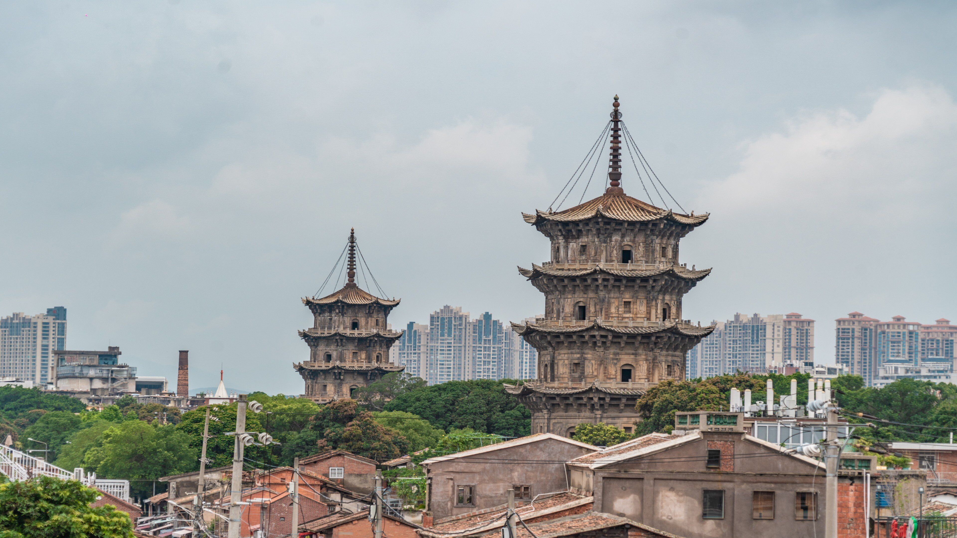 Un edificio de estilo pagoda tradicional con varios niveles, rodeado de modernos rascacielos y edificios residenciales.