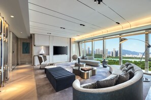 Una sala de estar moderna con un televisor grande, asientos cómodos y vistas a un paisaje urbano.