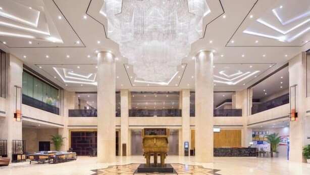 A spacious lobby with a central reception desk, high ceilings with geometric light fixtures, and a large decorative sculpture. - Tianfu Howard Easy Hotel (Funan)
