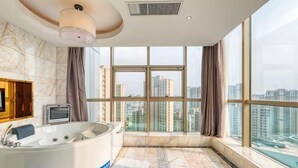A modern bathroom with a large bathtub, a vanity with a mirror, and a city view through large windows. - Tianfu Howard Easy Hotel (Funan)