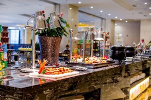A buffet setup with various food items and a decorative plant.