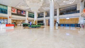 A spacious lobby with a high ceiling, a central column, and a reception desk.