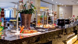 A buffet setup with various food items, a potted plant, and buffet lighting. - Tianfu Howard Easy Hotel (Funan)