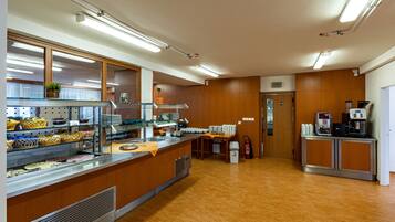 A spacious kitchen with wooden cabinets, a stainless steel counter, and a coffee machine.