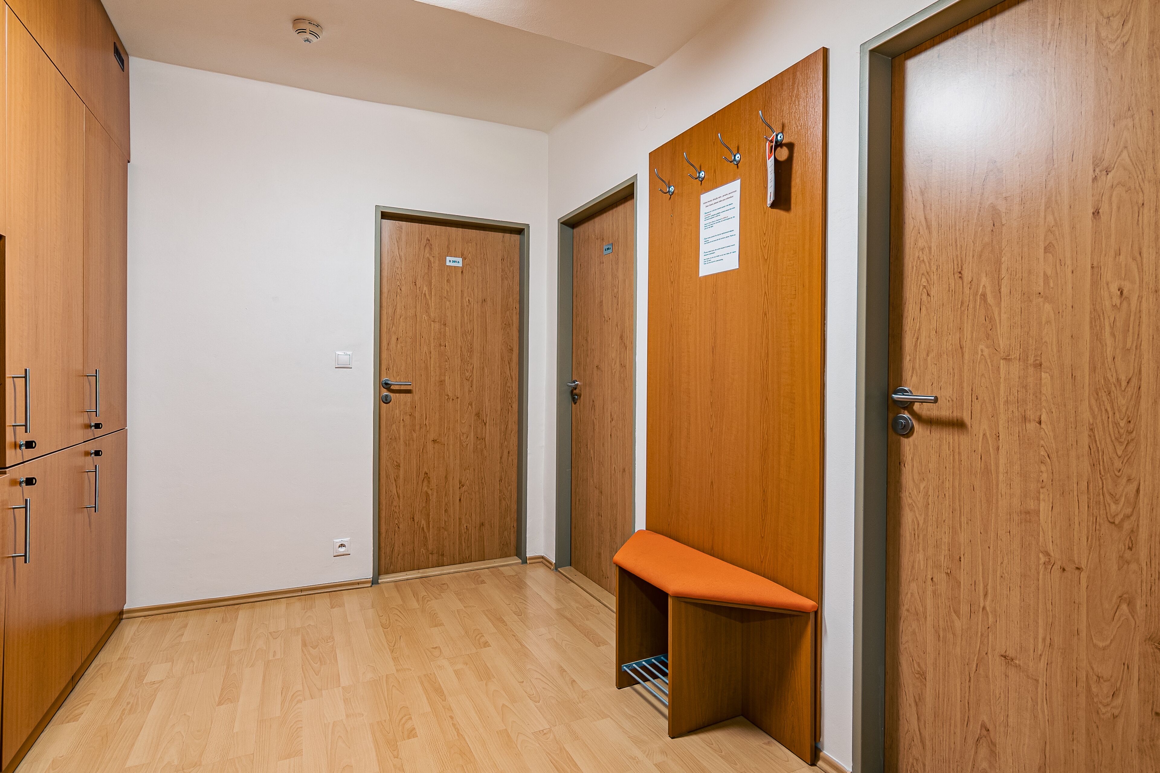 A hallway with wooden doors, a bench, and a coat rack.