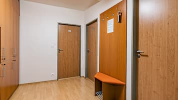 A hallway with wooden doors, a bench, and a coat rack.