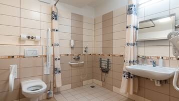 A bathroom with a toilet, shower, and sink.