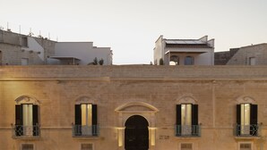 A building with a central arched entrance, multiple windows with shutters, and balconies with metal railings. - Calendula - Design apartment in historic building 5 min from Lecce (San Cesario di Lecce)