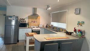 A modern kitchen with a built-in oven, a refrigerator, and a dining area with a table and chairs.