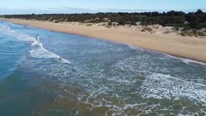 A beach with waves approaching the shore. - Golden Beachhouse - 5 mins from 90mile beach and shops (Golden Beach)