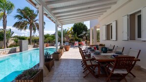 Un espace extérieur abrité, doté d’une piscine, de mobilier en bois et offrant une vue sur le paysage environnant.