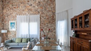 Un salon avec un mur en pierre, une table à manger en verre, un canapé et un meuble en bois.
