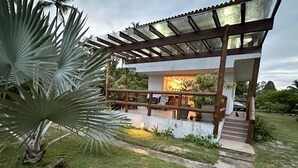 A covered outdoor area with a wooden railing, a concrete pathway, and a palm tree. - Glass lacquer! Jacuzzi on the sand with gourmet area! (BA)