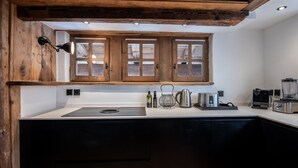 A kitchen with wooden cabinets, a sink, a kettle, a coffee maker, and a blender. - Luxury Chalet in Courchevel with Pool, Hammam and Sauna (Courchevel 1850)