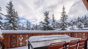 A wooden deck with a table and chairs, surrounded by snow-covered trees and mountains in the background. - Luxury Chalet in Courchevel with Pool, Hammam and Sauna (Courchevel 1850)