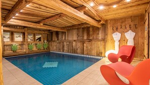 A wooden interior with a pool, red chairs, and a 'CHALET' sign. - Luxury Chalet in Courchevel with Pool, Hammam and Sauna (Courchevel 1850)