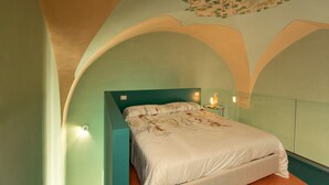 A bedroom with a bed, a nightstand, and a wall-mounted lamp.
