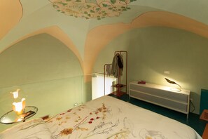 A bedroom with a bed, a bedside table with a lamp, a wardrobe, and a mirror. - Melissa - Designer apartment in historic building 5 min from Lecce (San Cesario di Lecce)