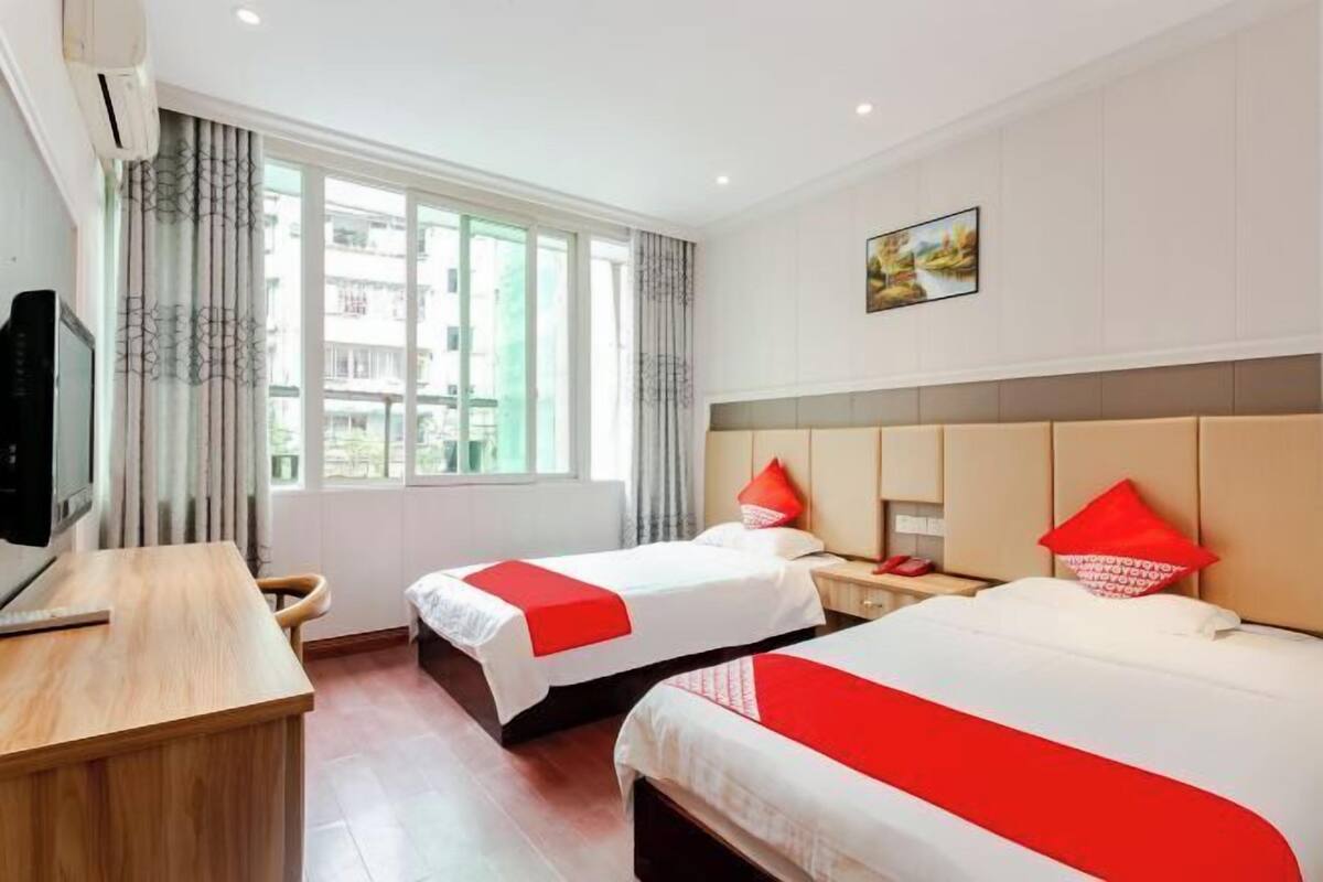 Habitación de hotel con dos camas, un escritorio, un televisor y una ventana con cortinas.