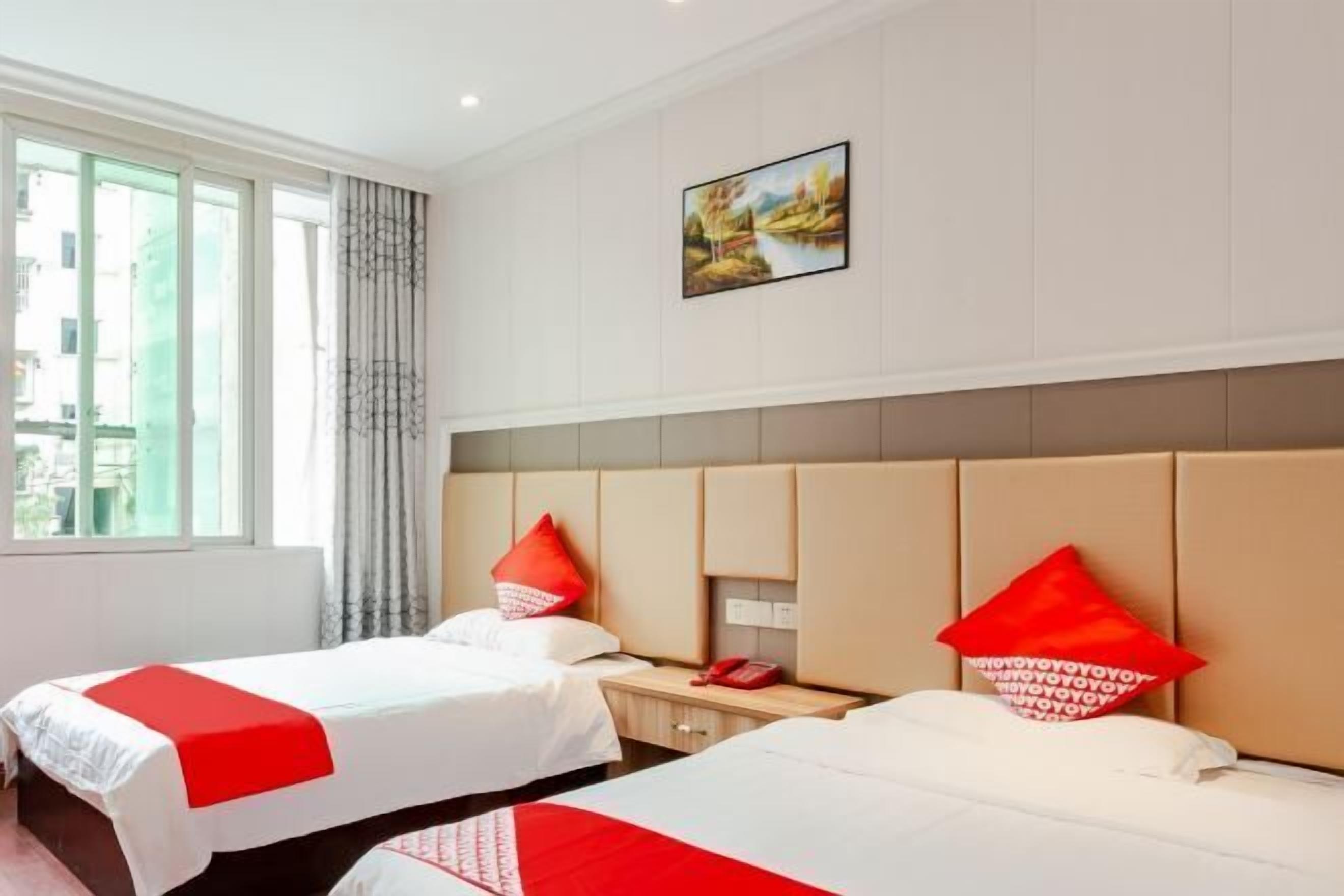A hotel room with two beds, a window with curtains, a painting on the wall, and a telephone on the nightstand.